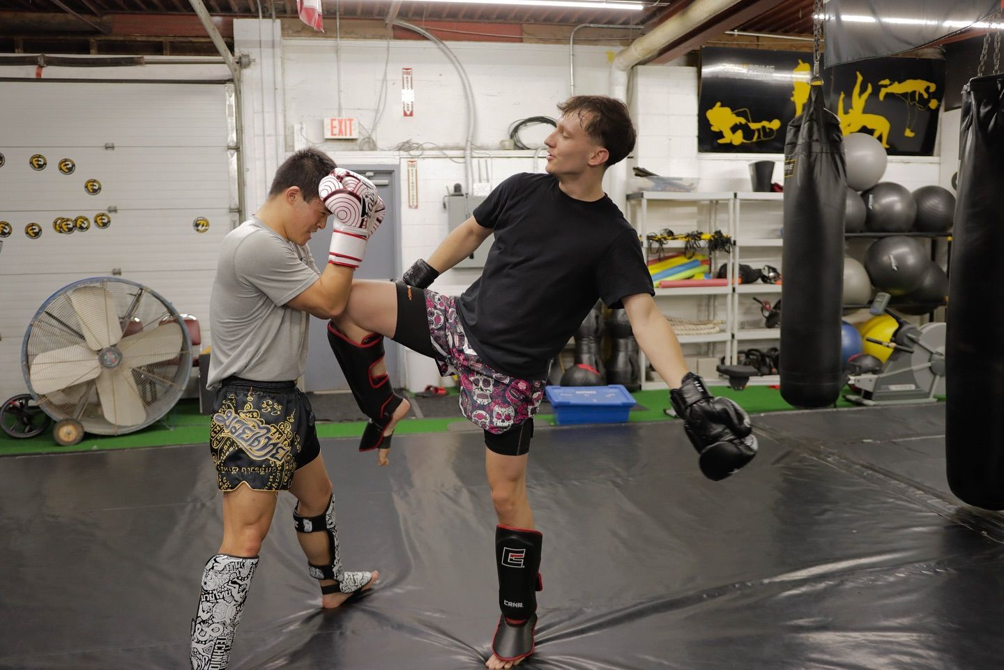 Two men are practicing martial arts in a gym.