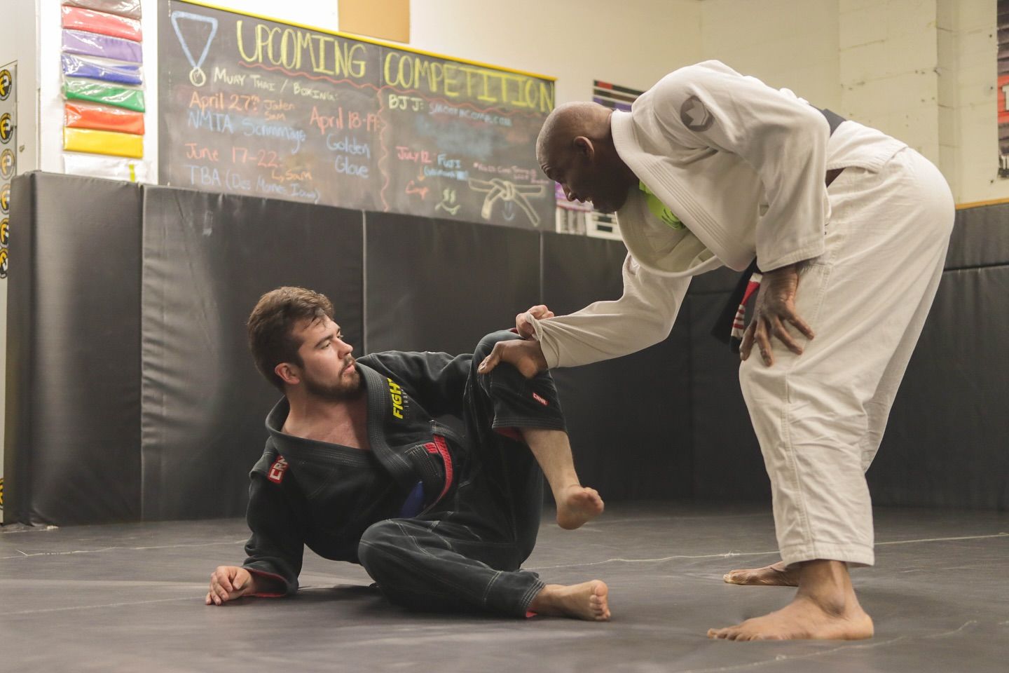 Two men are practicing martial arts in a gym.