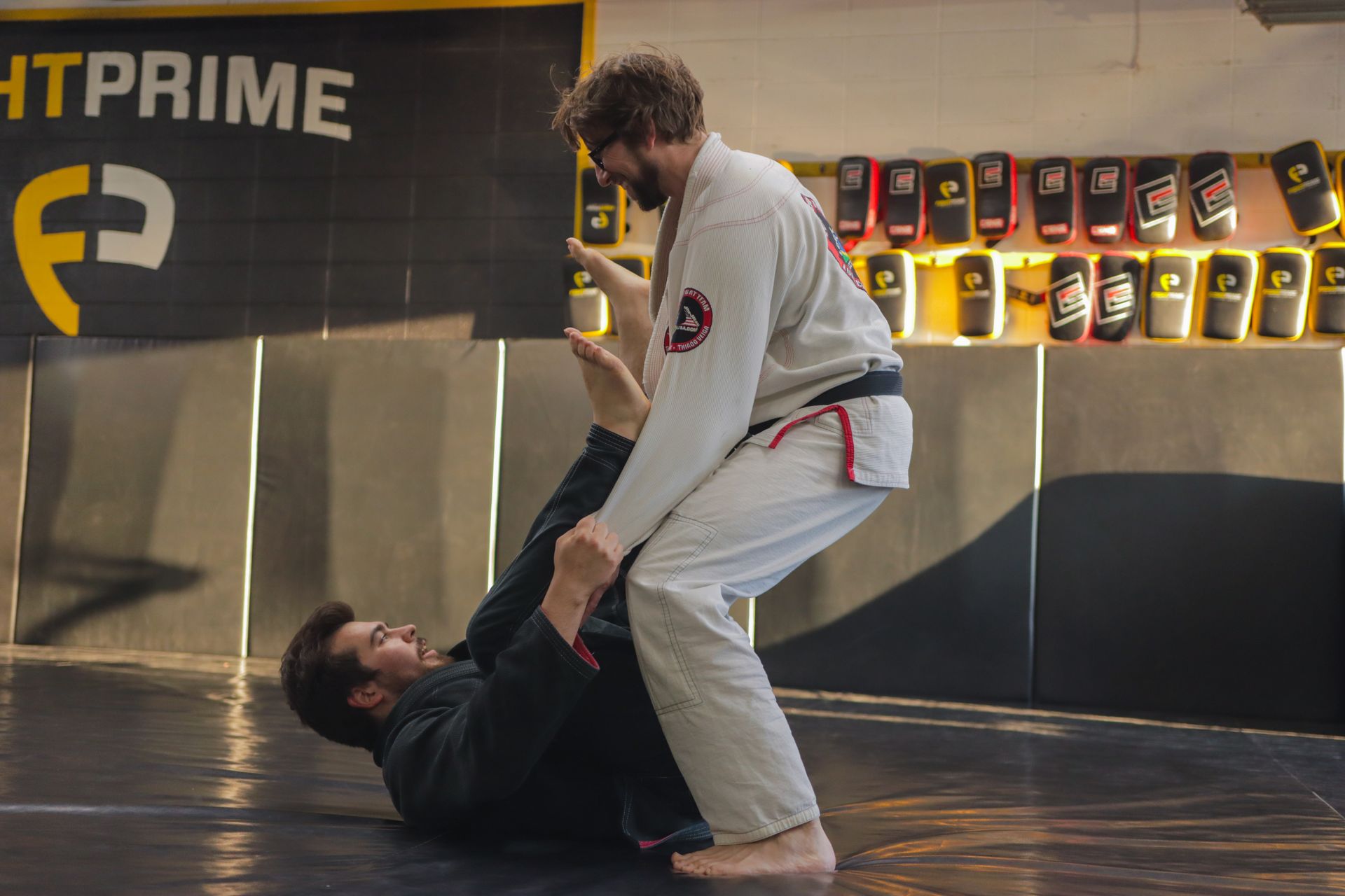 Two men are practicing jiu jitsu in a gym.