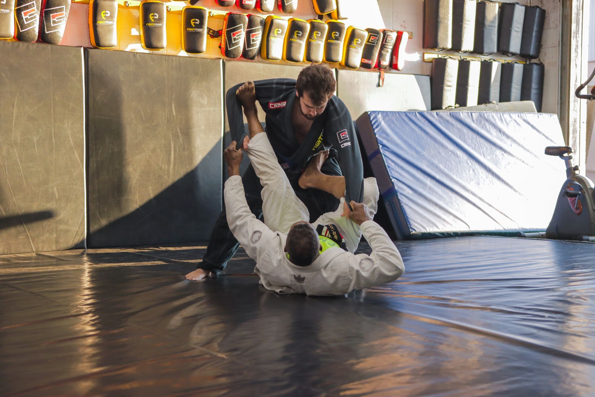 Two men are wrestling on a mat in a gym.