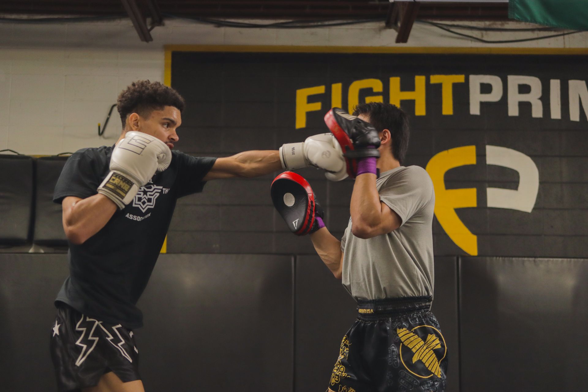 Two men are boxing in front of a sign that says fightprim