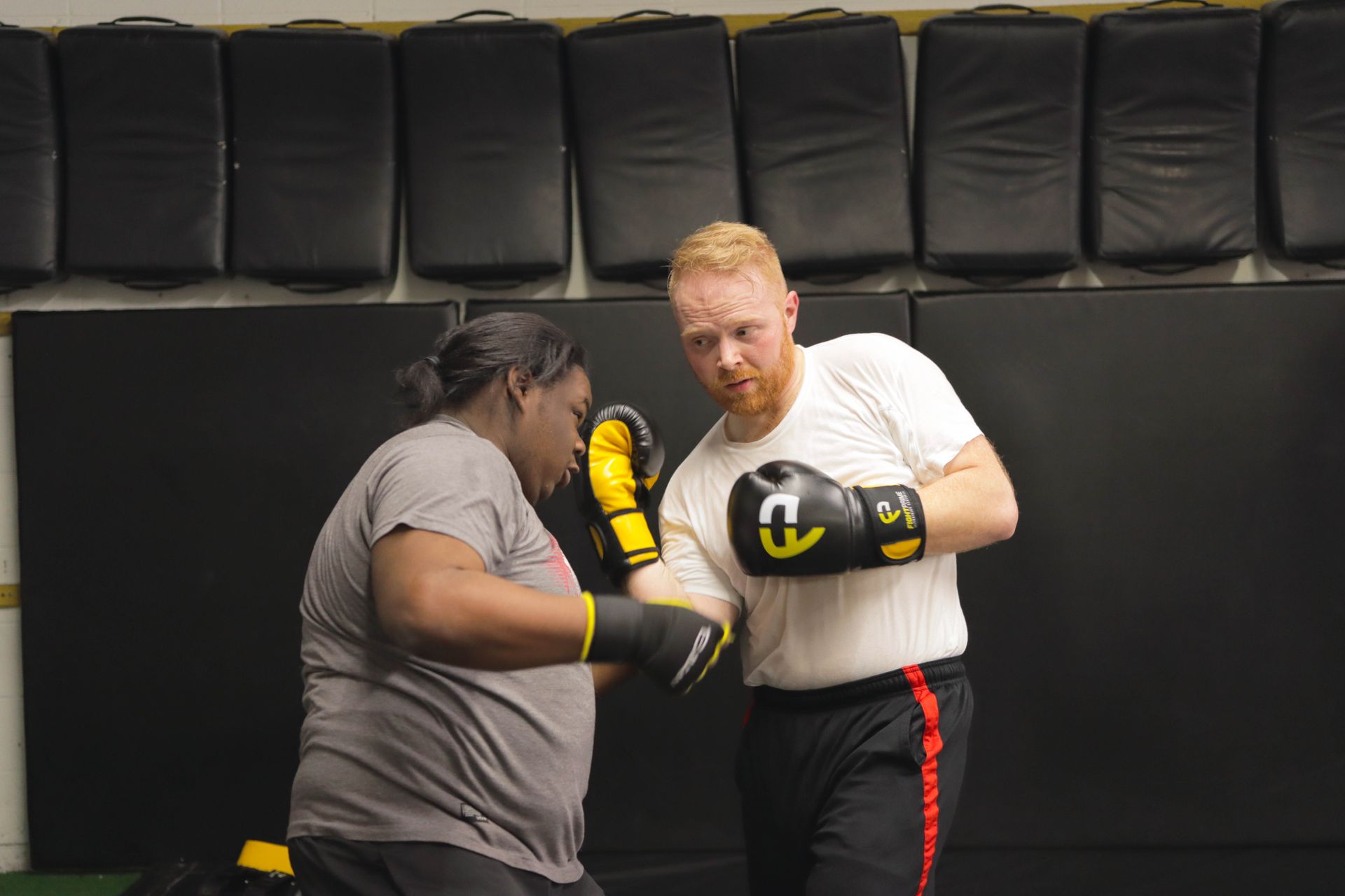 A man and a woman are boxing in a gym.