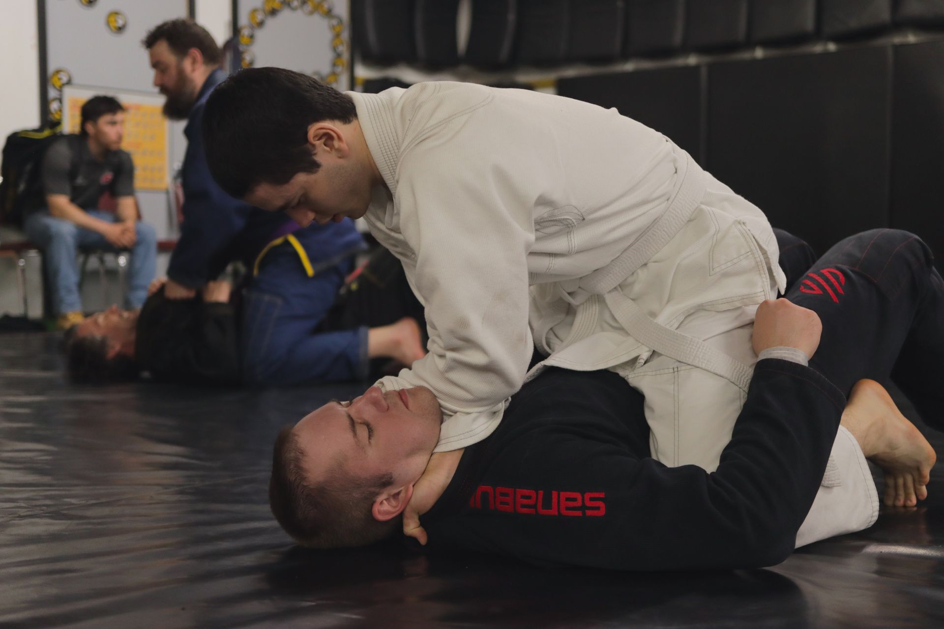 A group of men are wrestling on a mat in a gym.