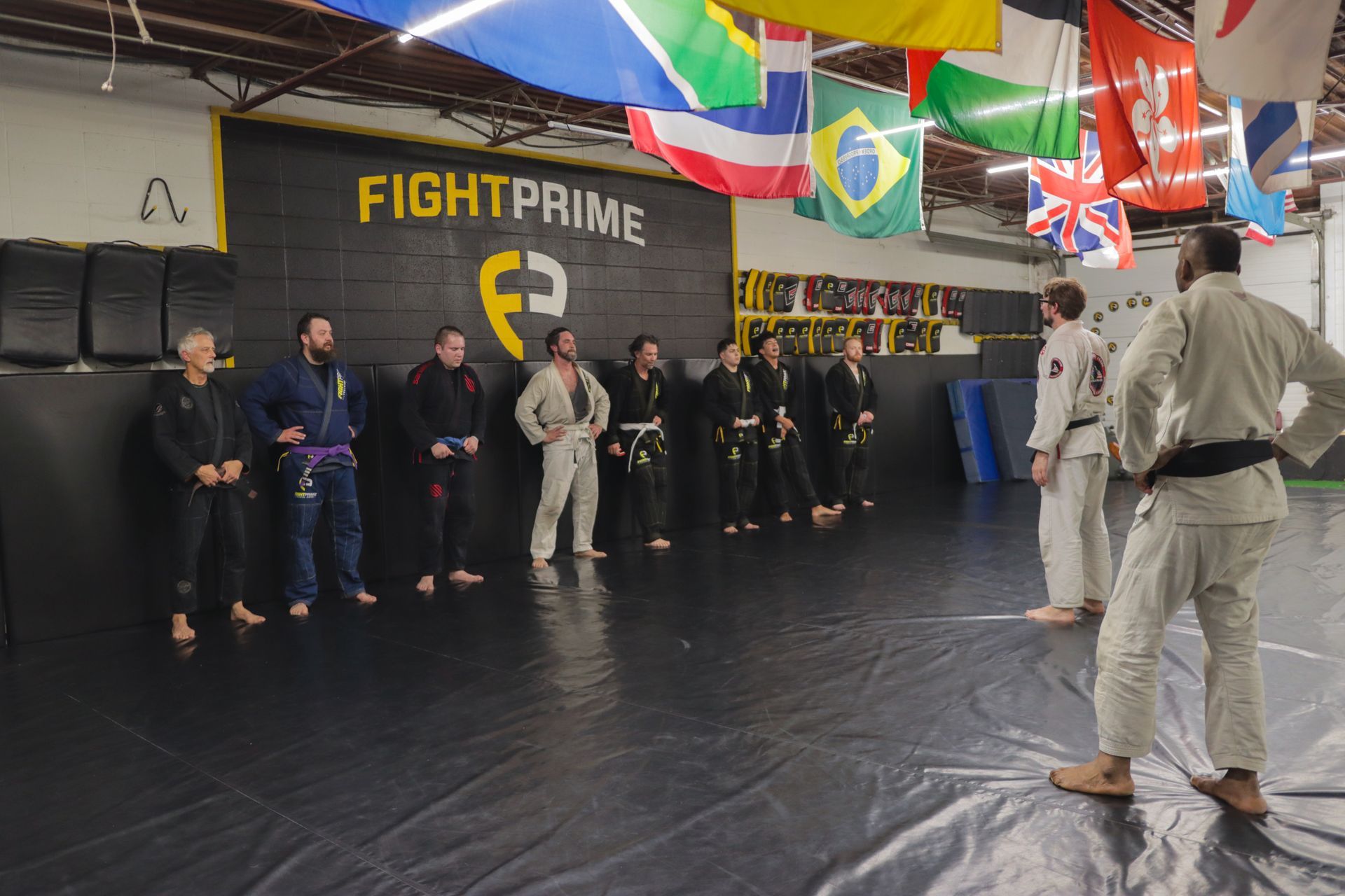 A group of people are standing in a gym with flags hanging from the ceiling.