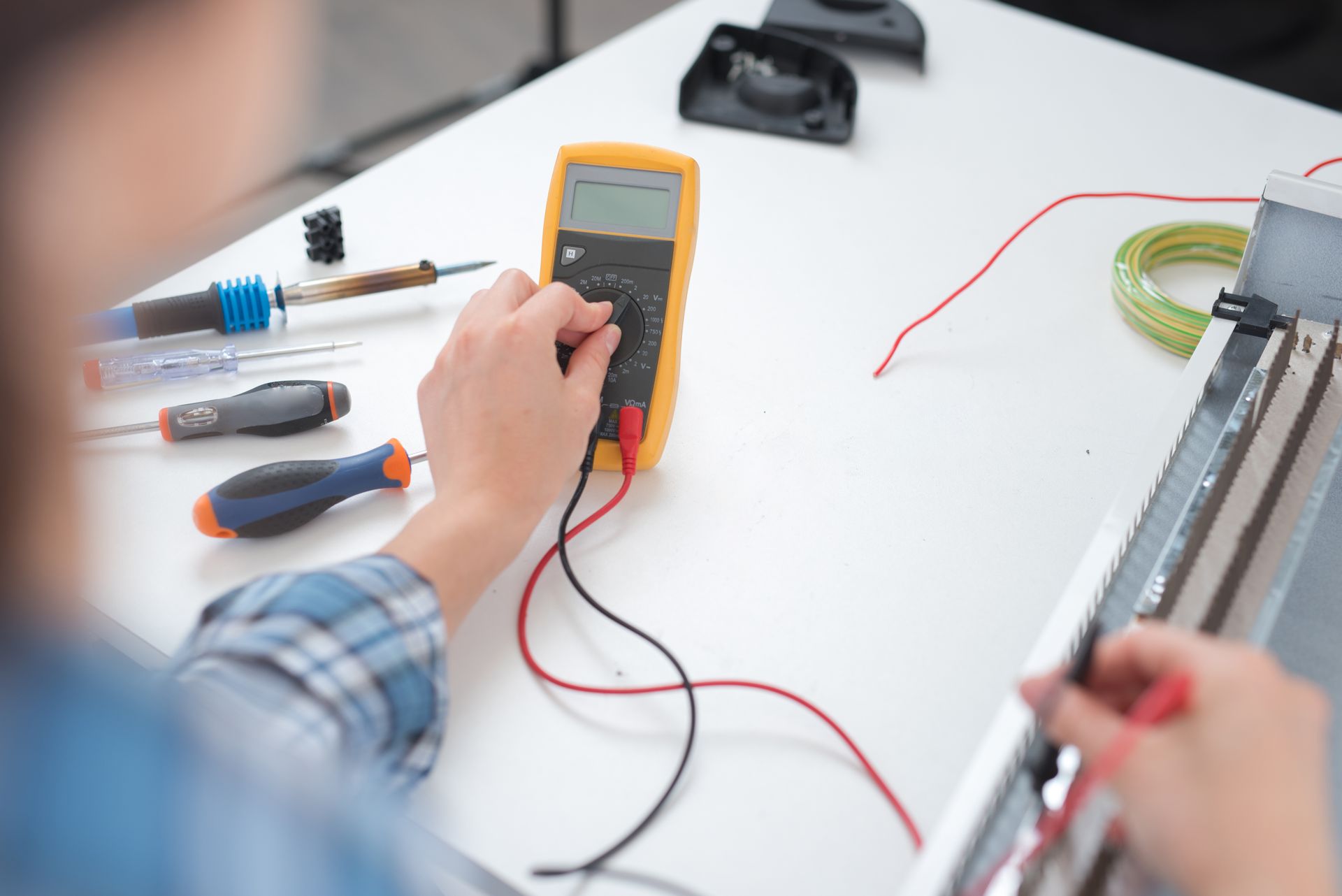 A man is using a multimeter to test a wire.