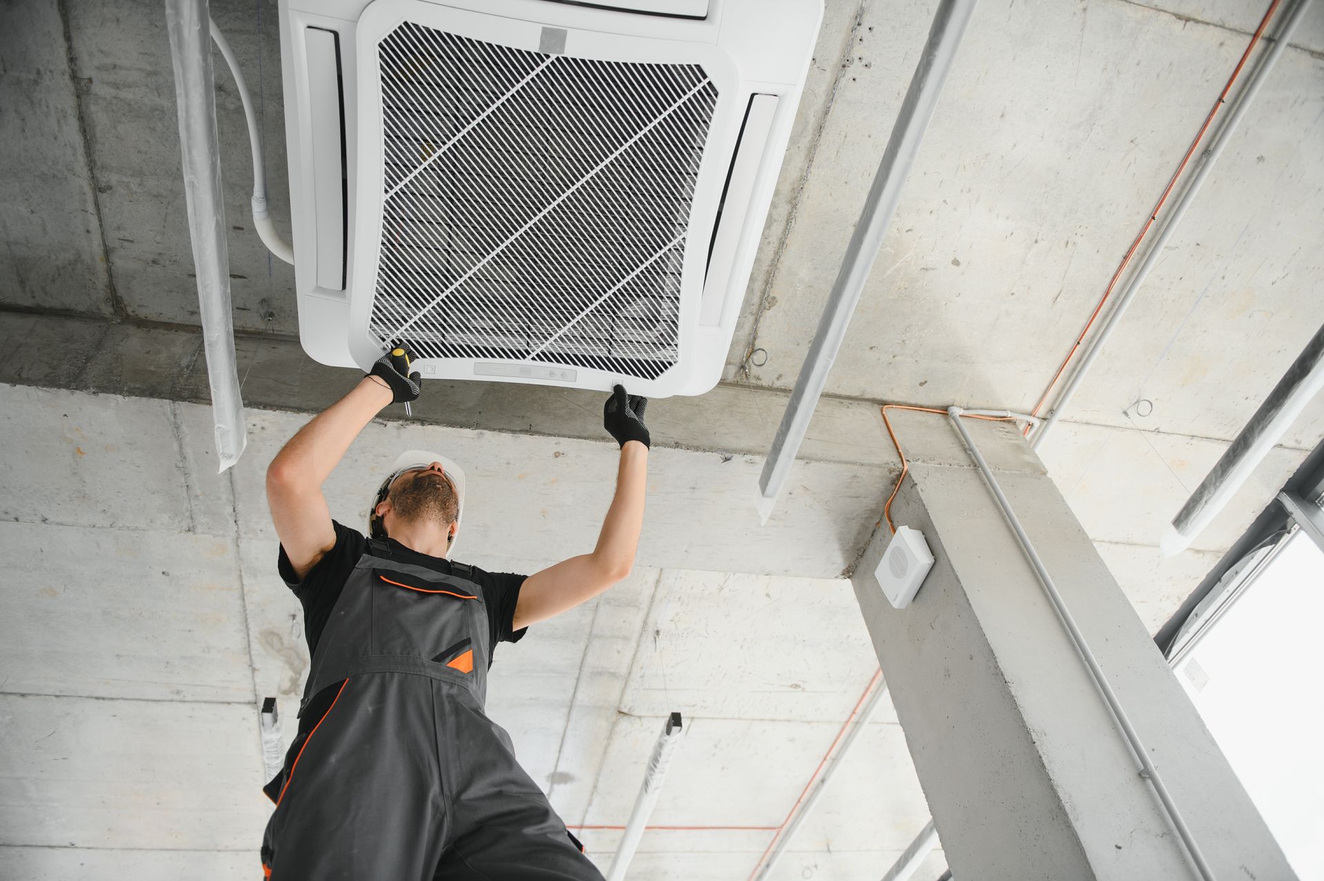 A man is working on a ceiling fan in a building.