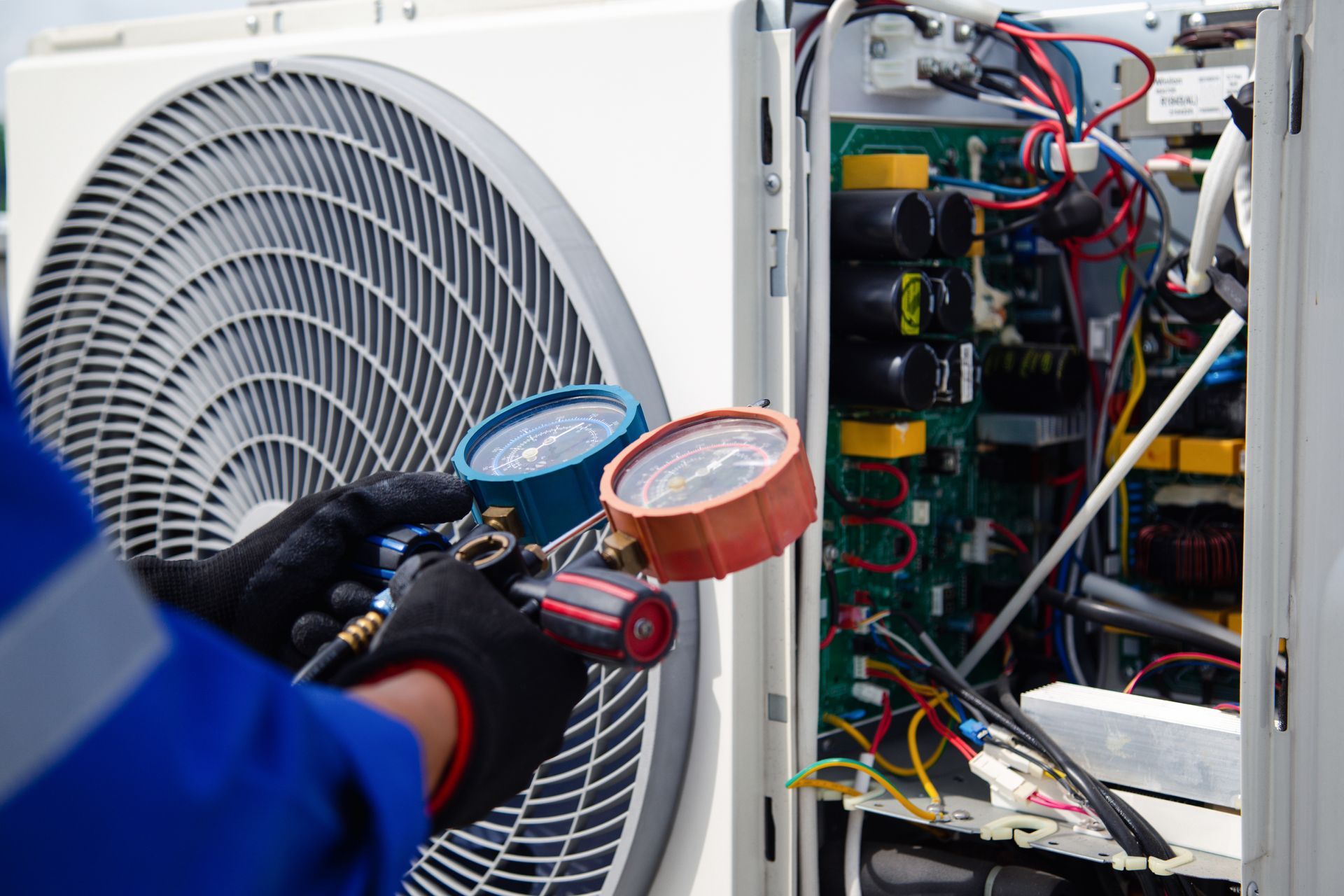 A man is working on an air conditioner with a pressure gauge.