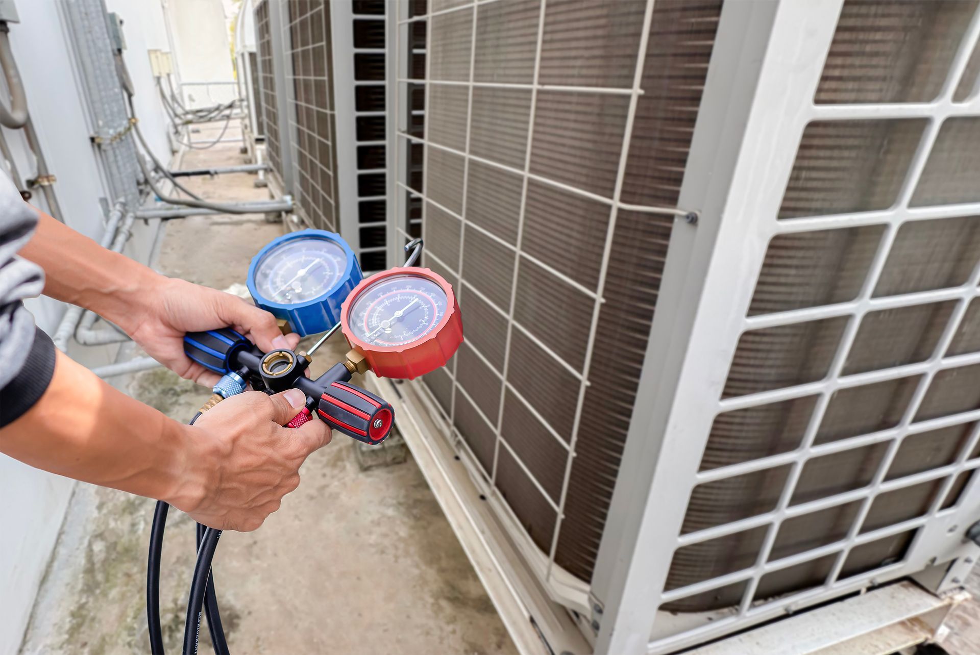 A man is working on an air conditioner outside of a building.