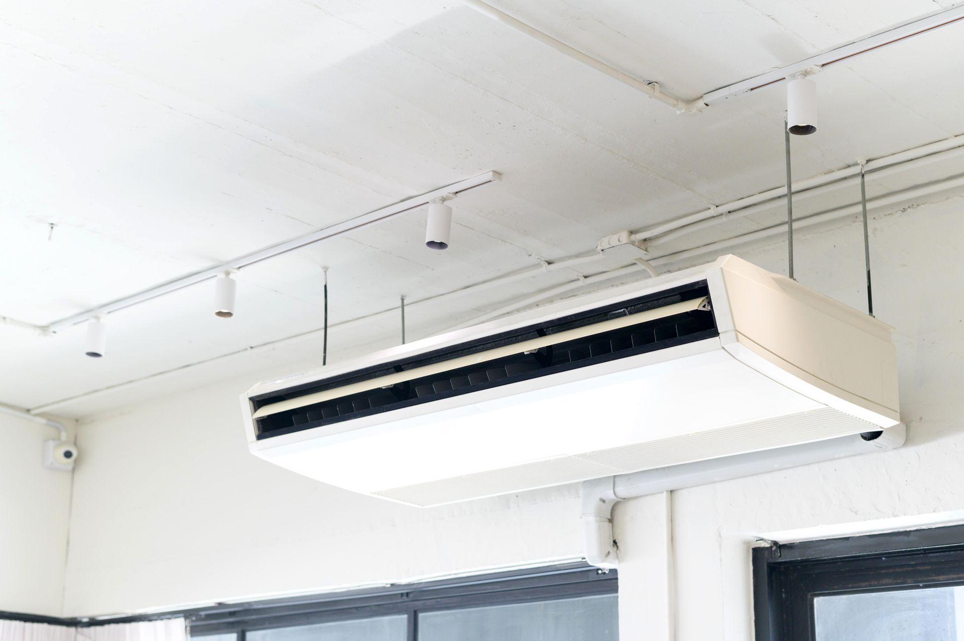 A ceiling mounted air conditioner is hanging from the ceiling of a room.