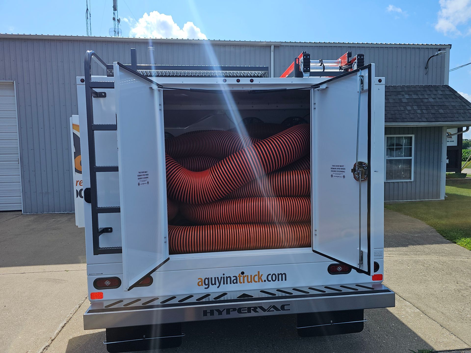 Rear view of A Guy in a Truck air duct cleaning vehicle with large hoses stored inside.