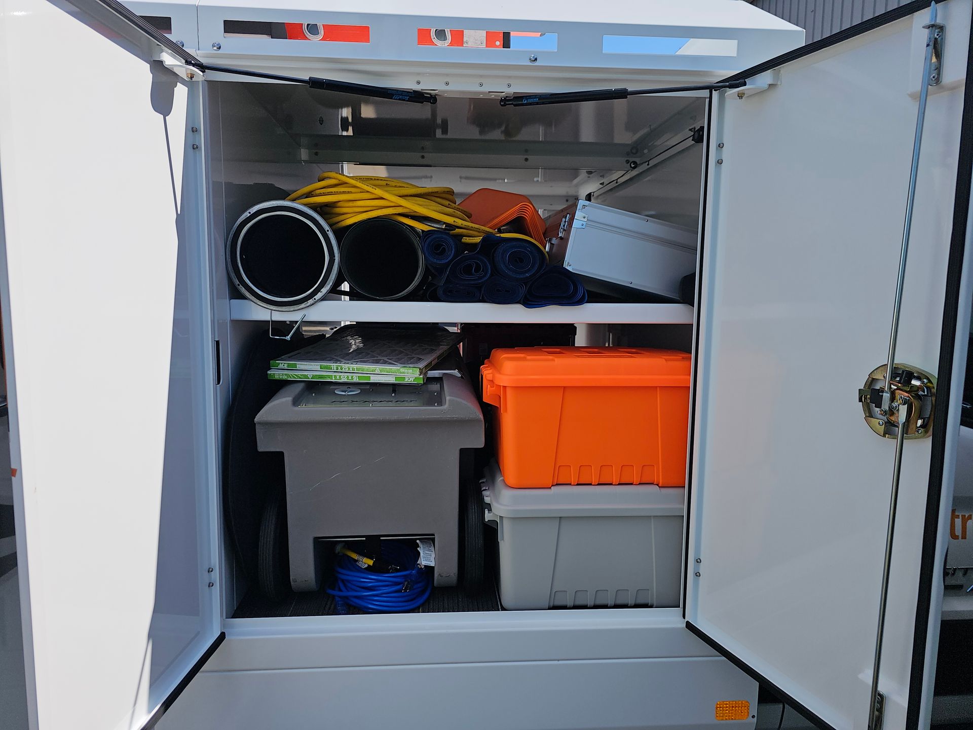 Storage compartment of A Guy in a Truck air duct cleaning vehicle with hoses and tools inside.