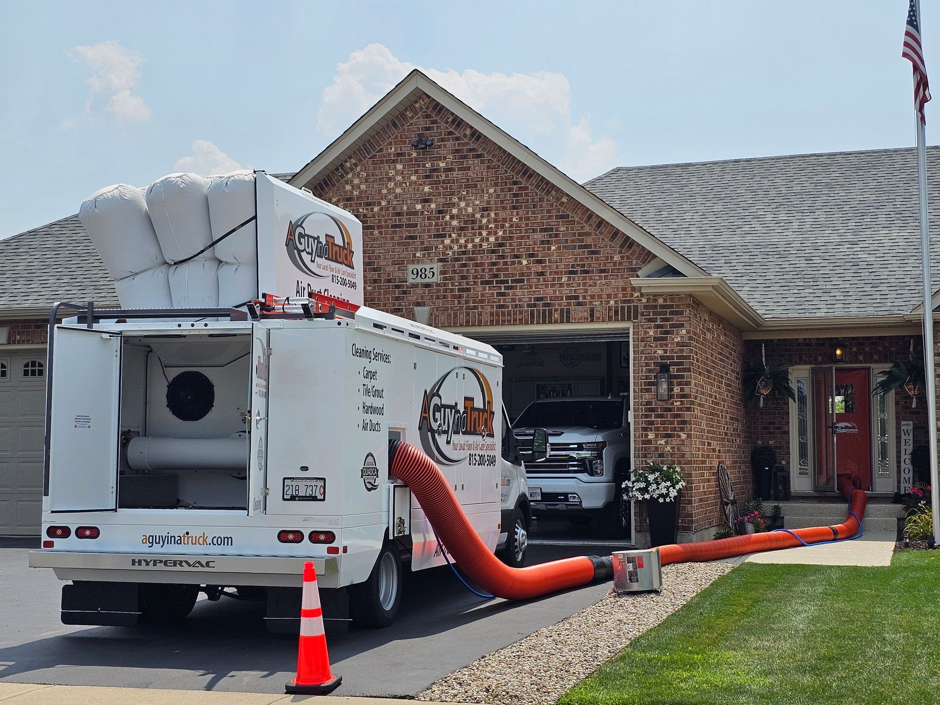 A Guy in a Truck air duct cleaning truck servicing a home with vacuum hose connected for residential duct cleaning.