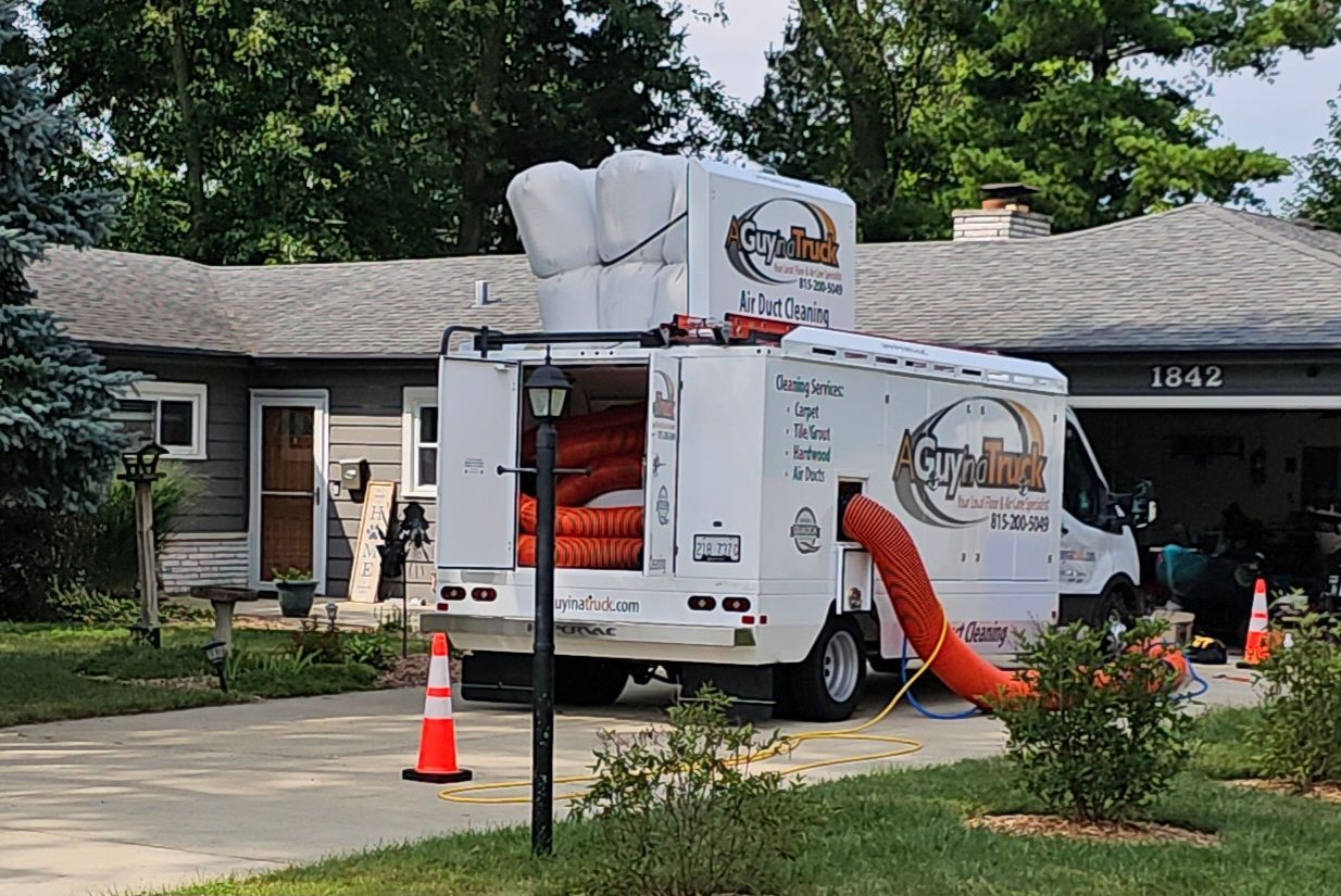 A Guy in a Truck commercial air duct cleaning truck with vacuum hoses servicing building ventilation system.