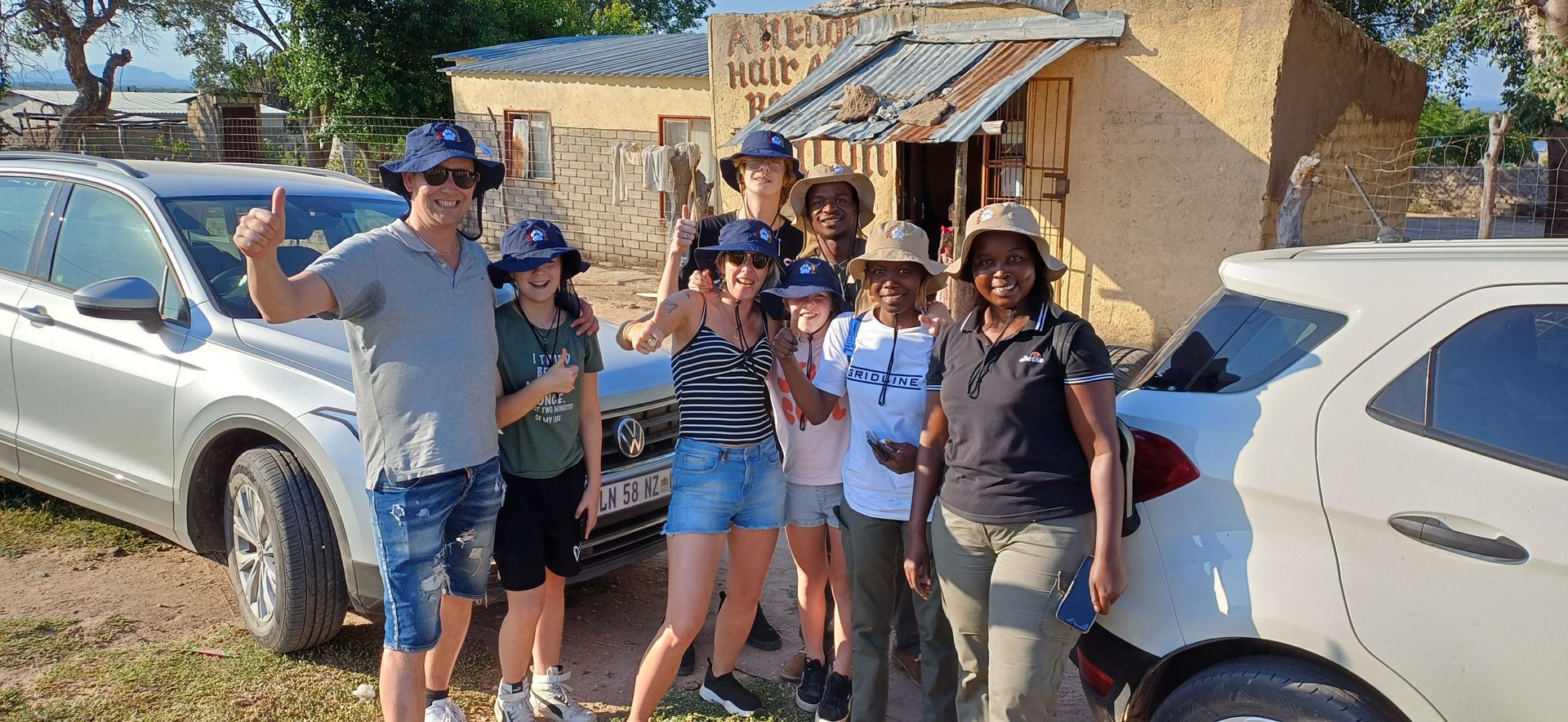A group of people are posing for a picture in front of a car.