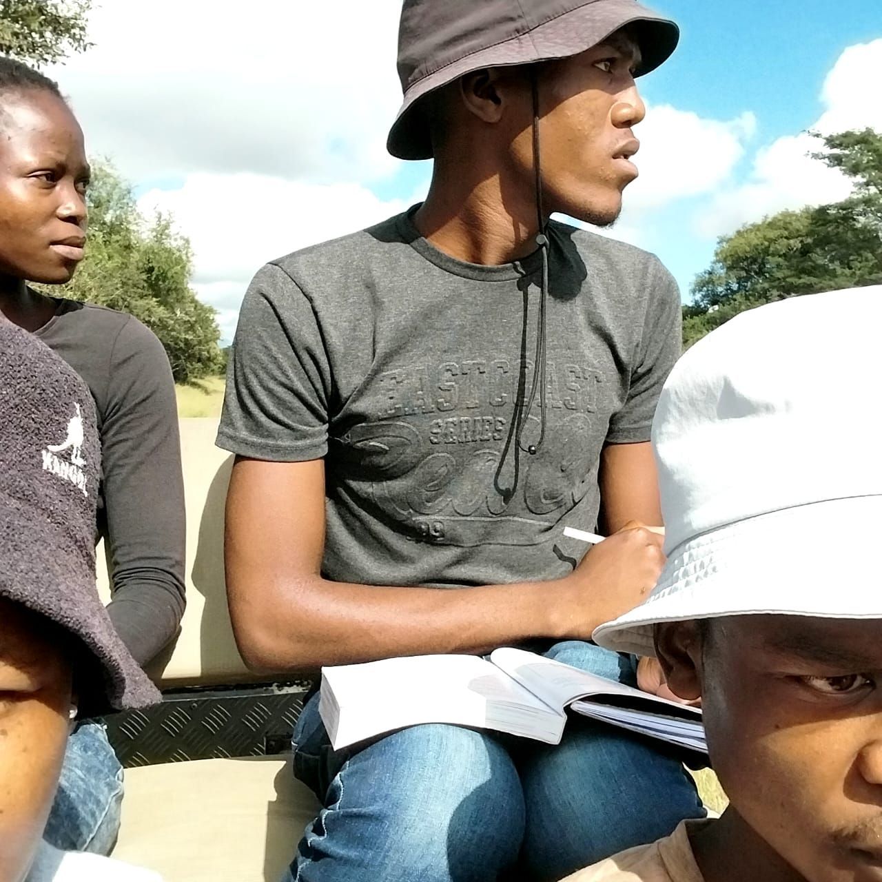 A man wearing a hat is sitting next to two other people