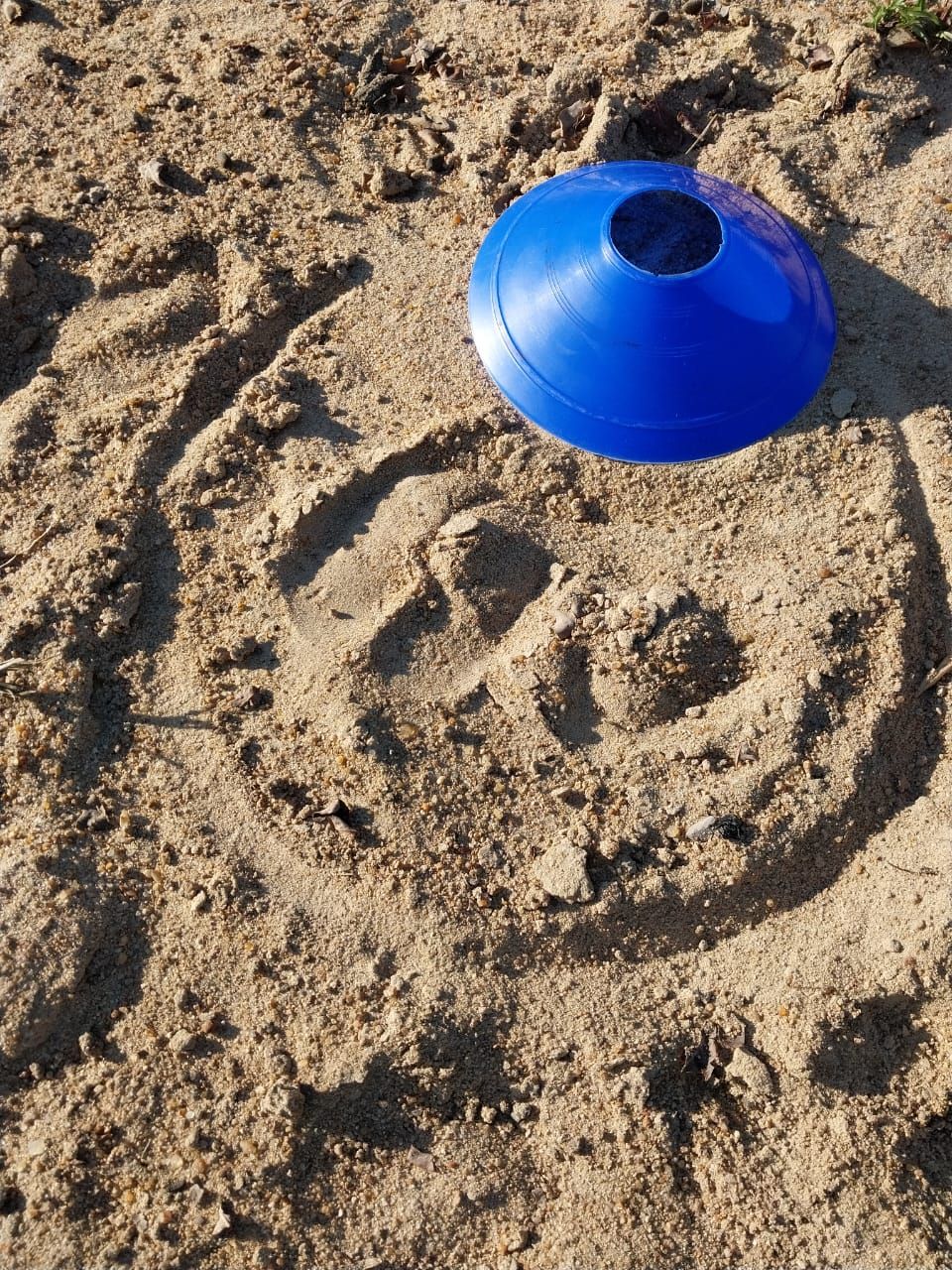 A blue cone is sitting on top of a pile of sand.