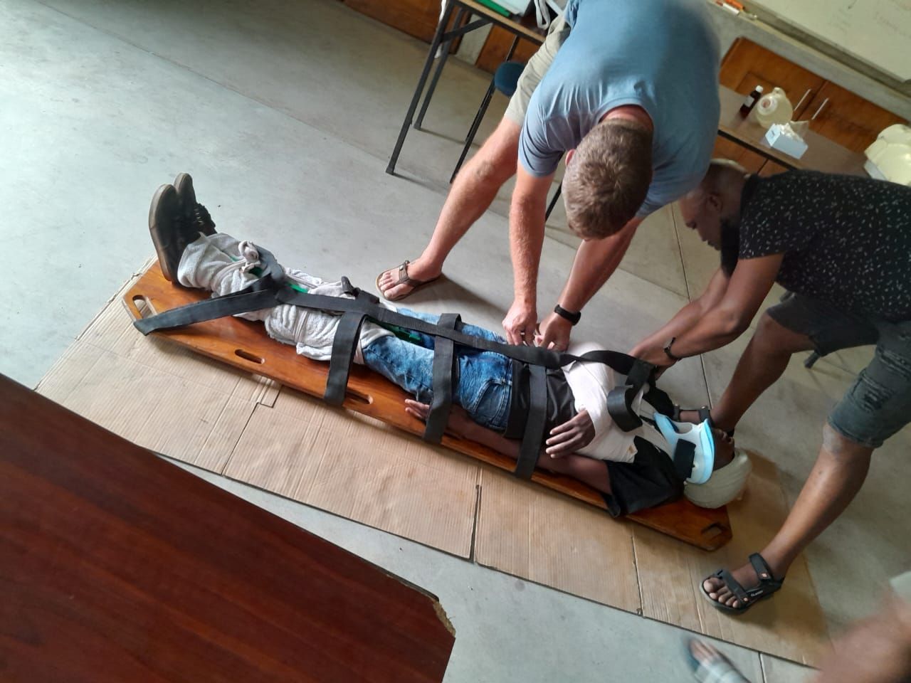 Two men are helping a person on a stretcher