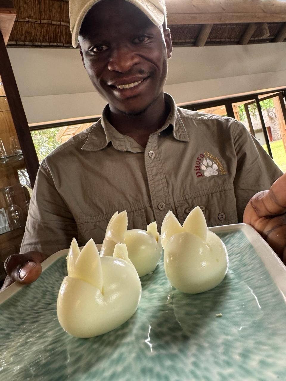 A man is smiling while holding a plate of eggs in the shape of rabbits.