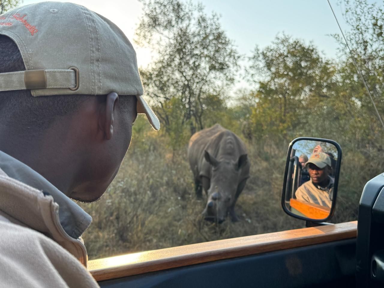 A man is looking out of a car window at a rhino
