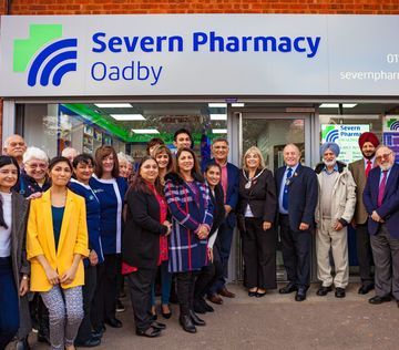 A group of people are posing for a picture in front of a pharmacy.