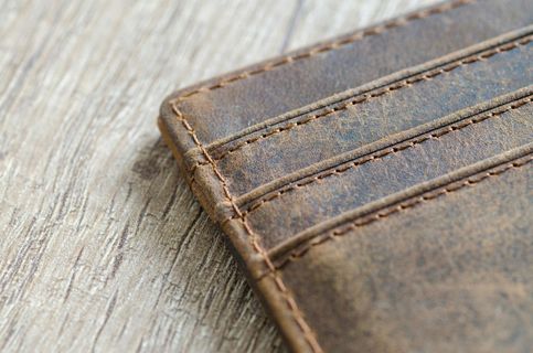 A close up of a brown leather wallet on a wooden table.