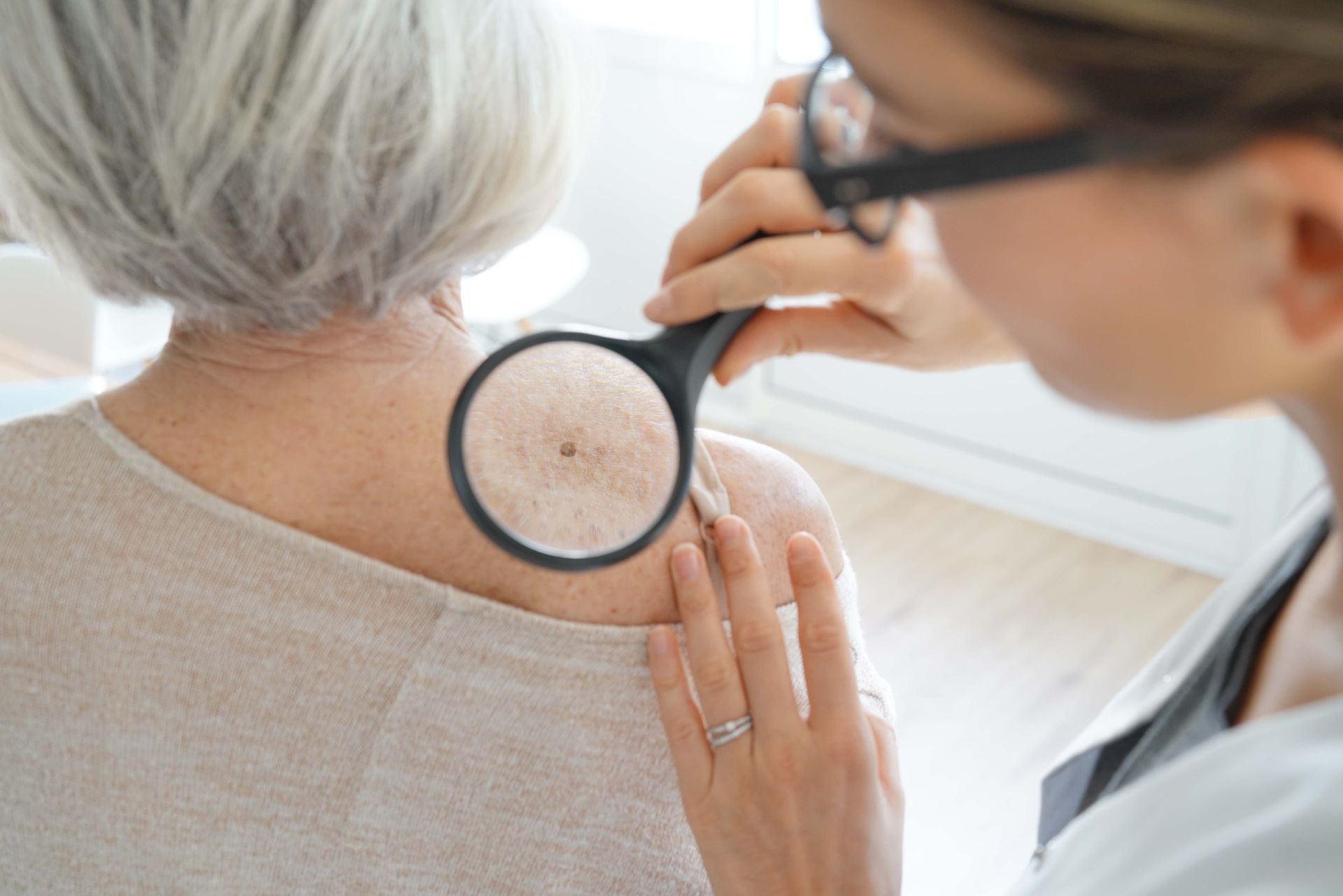 Senior woman getting skin checked by dermatologist.