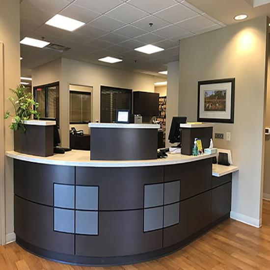 A reception desk in a office with a picture on the wall above it