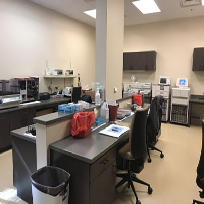 A laboratory with a lot of desks and chairs and a trash can.