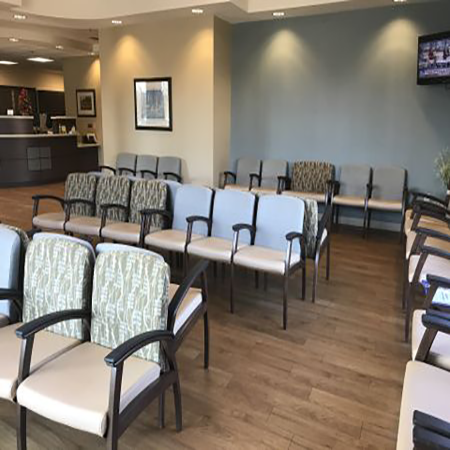 A waiting room with a lot of chairs and a television on the wall.