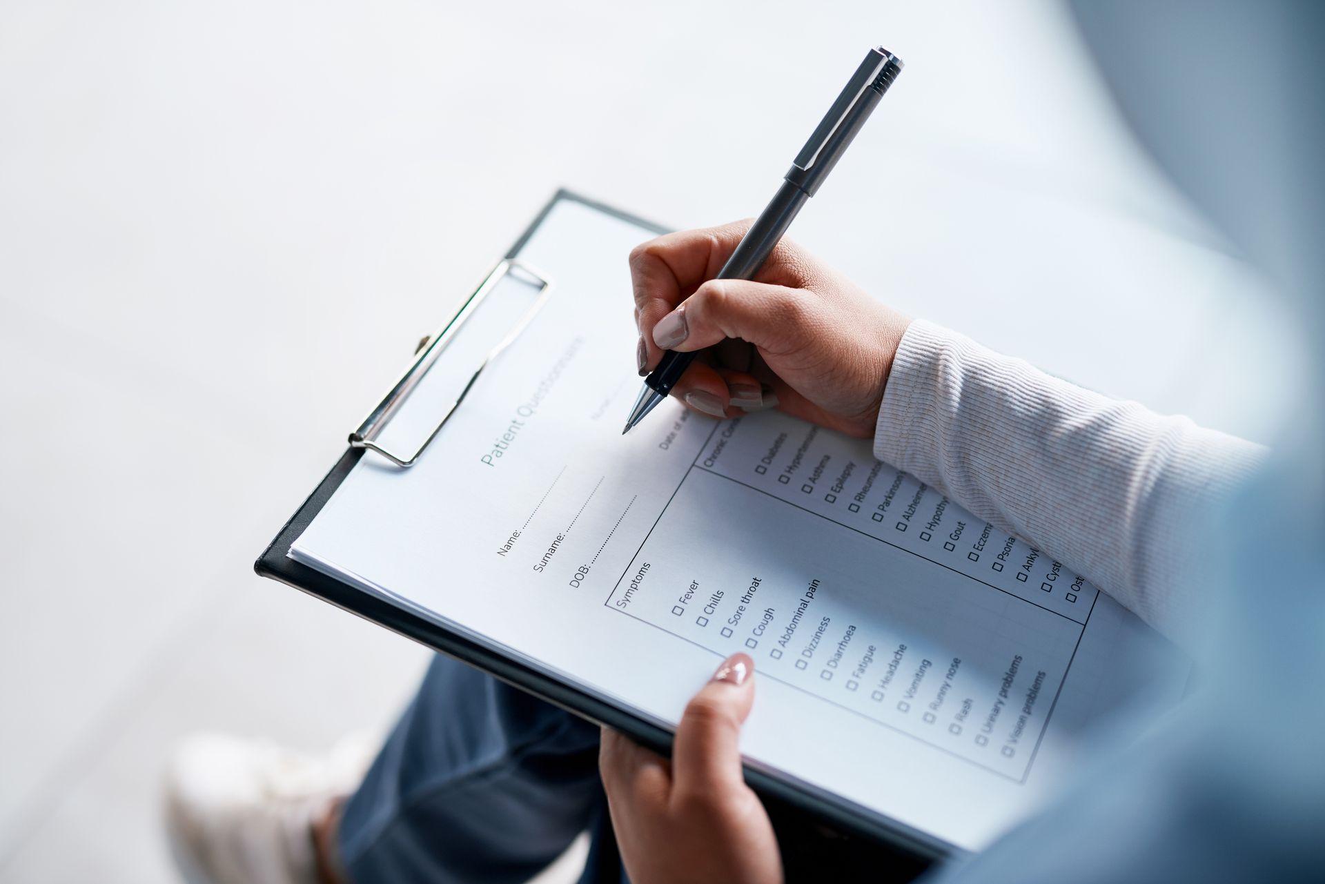 A person is writing on a clipboard with a pen.