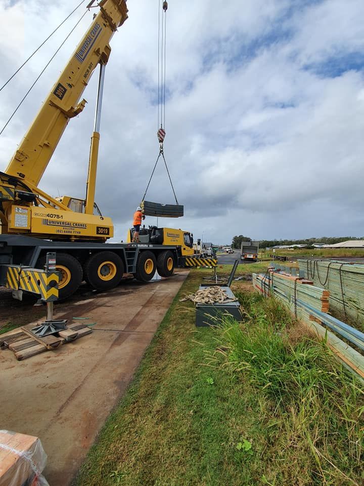A Large Yellow Crane is Lifting a Large Piece of Wood — Jason Walsh Constructions in Alstonville, NSW