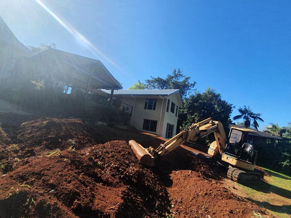 An Excavator is Digging a Hole in Front of a House — Jason Walsh Constructions in Alstonville, NSW