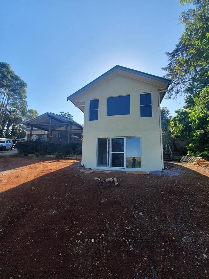 A House With a Lot of Windows is Sitting in the Middle of a Dirt Field — Jason Walsh Constructions in Lismore, NSW