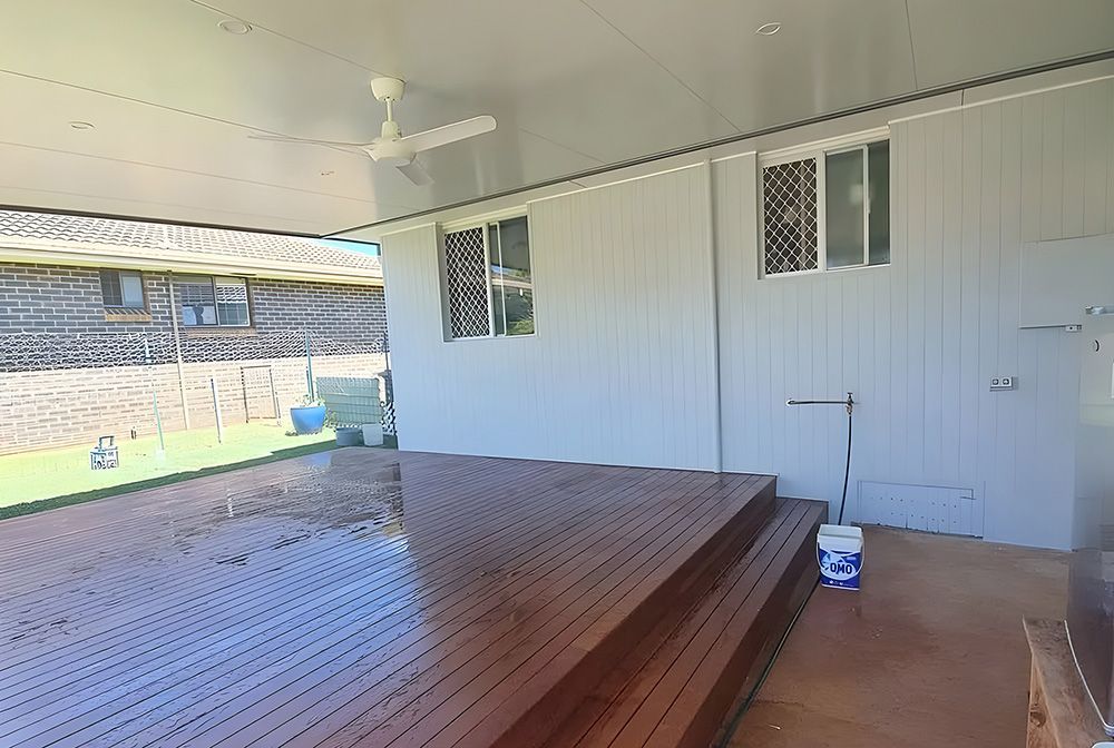 Covered Patio with Stained Wooden Deck and White Walls