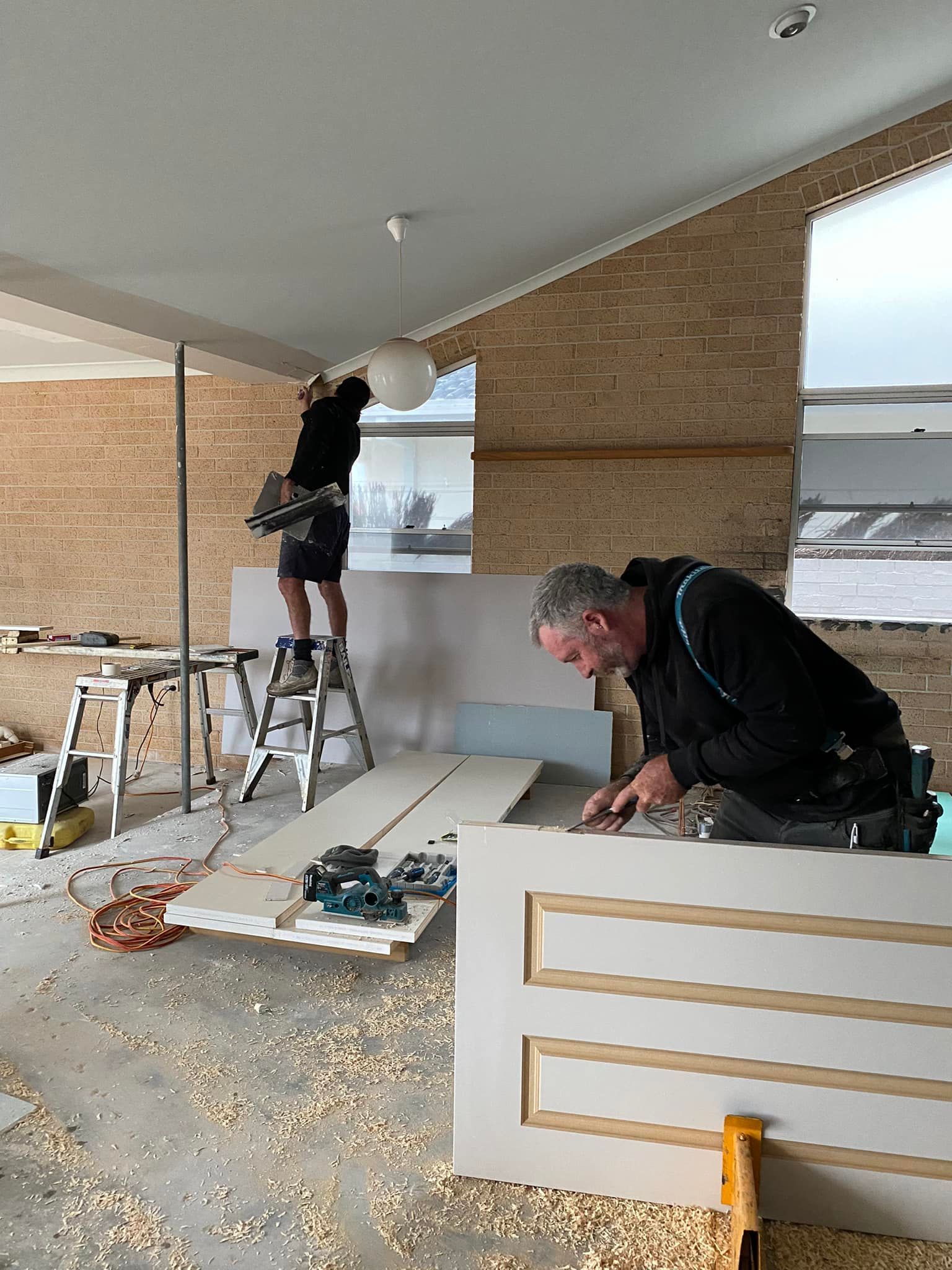 Two men are working on a door in a room — Jason Walsh Constructions in Alstonville, NSW
