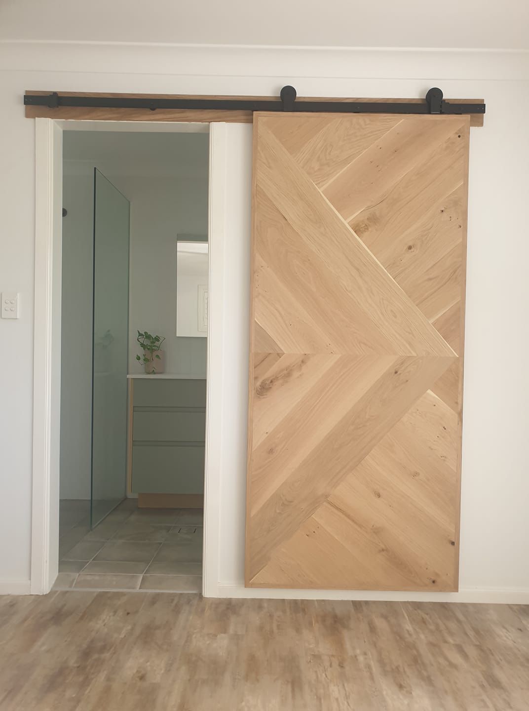 A Wooden Sliding Barn Door is Open to a Bathroom — Jason Walsh Constructions in Alstonville, NSW