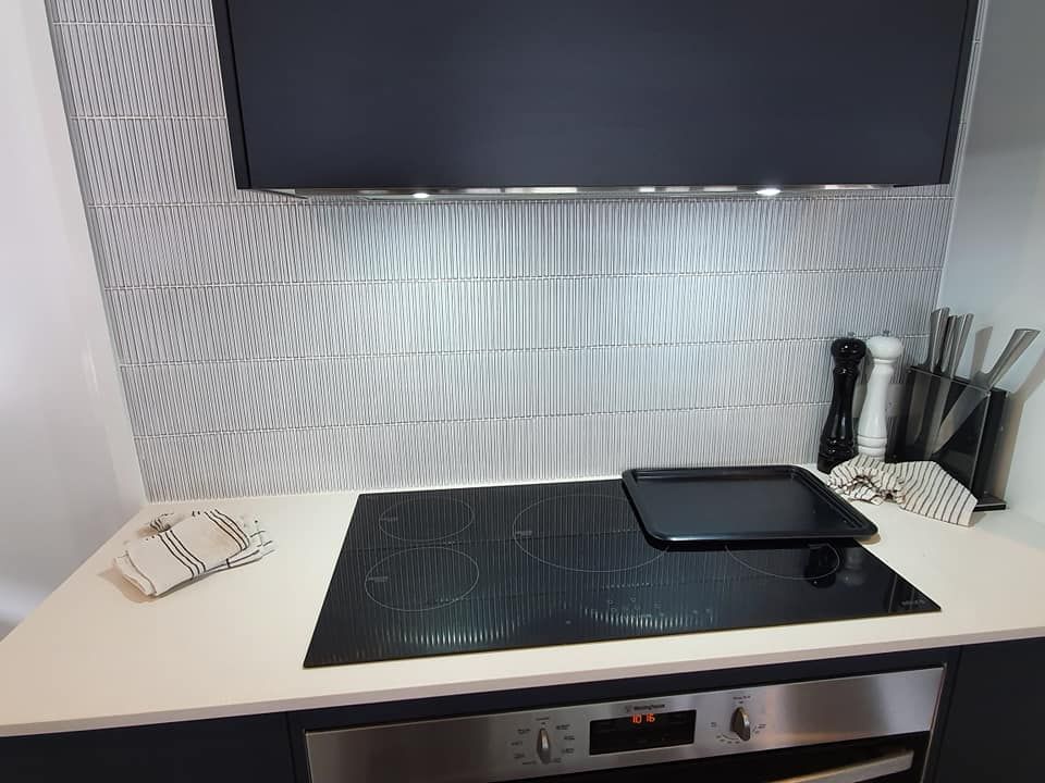 A Kitchen With a Black Stove Top Oven and Stainless Steel Appliances — Jason Walsh Constructions in Lismore, NSW