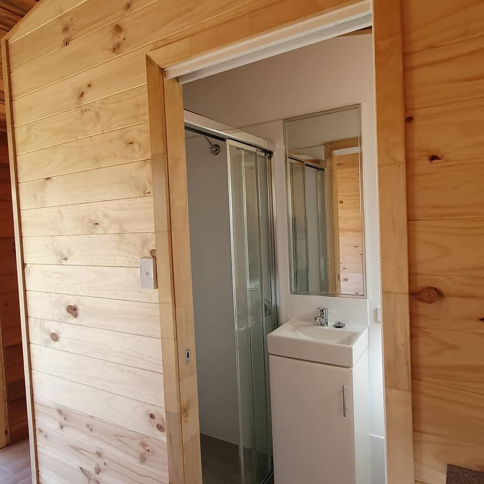 A Bathroom With Wooden Walls and a Sink and Shower — Jason Walsh Constructions in Byron Bay, NSW