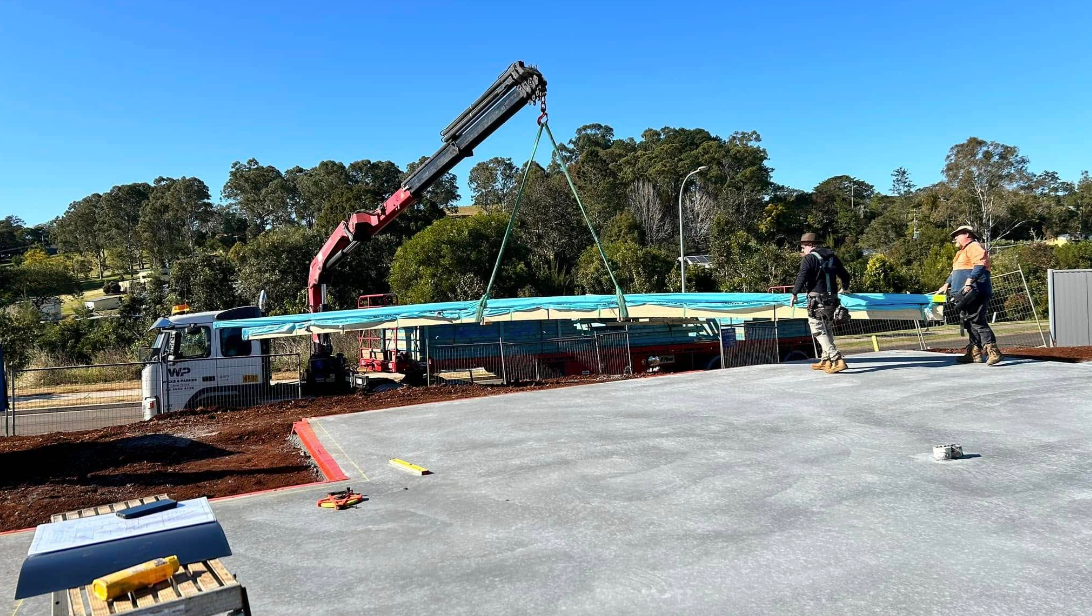 A crane is lifting a large piece of wood on a construction site — Jason Walsh Constructions in Alstonville, NSW