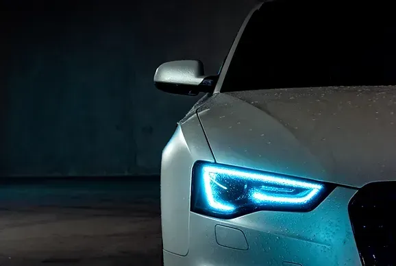 Un gros plan des phares d'une voiture dans une pièce sombre.