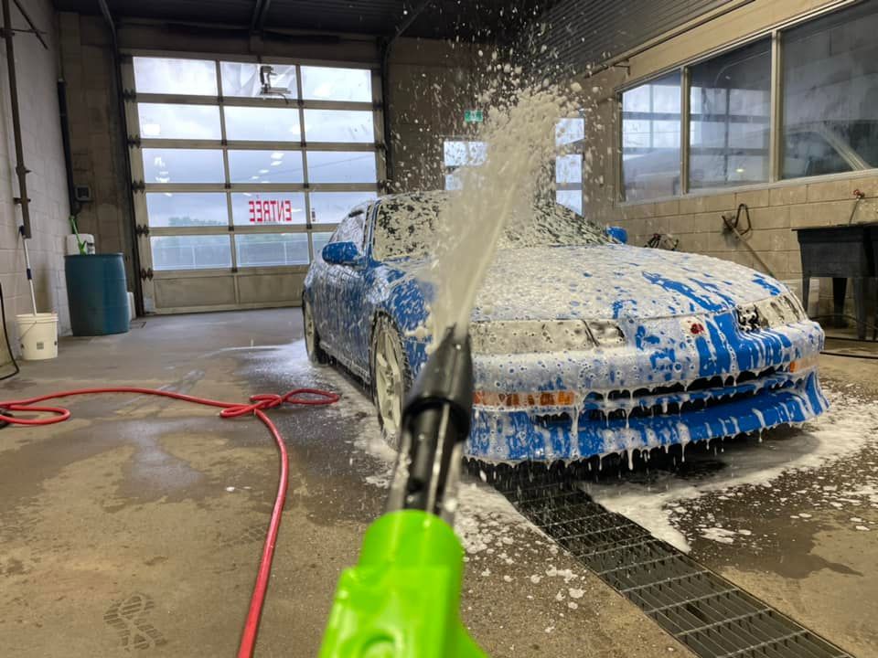 Une voiture bleue est lavée avec de la mousse dans un lave-auto.