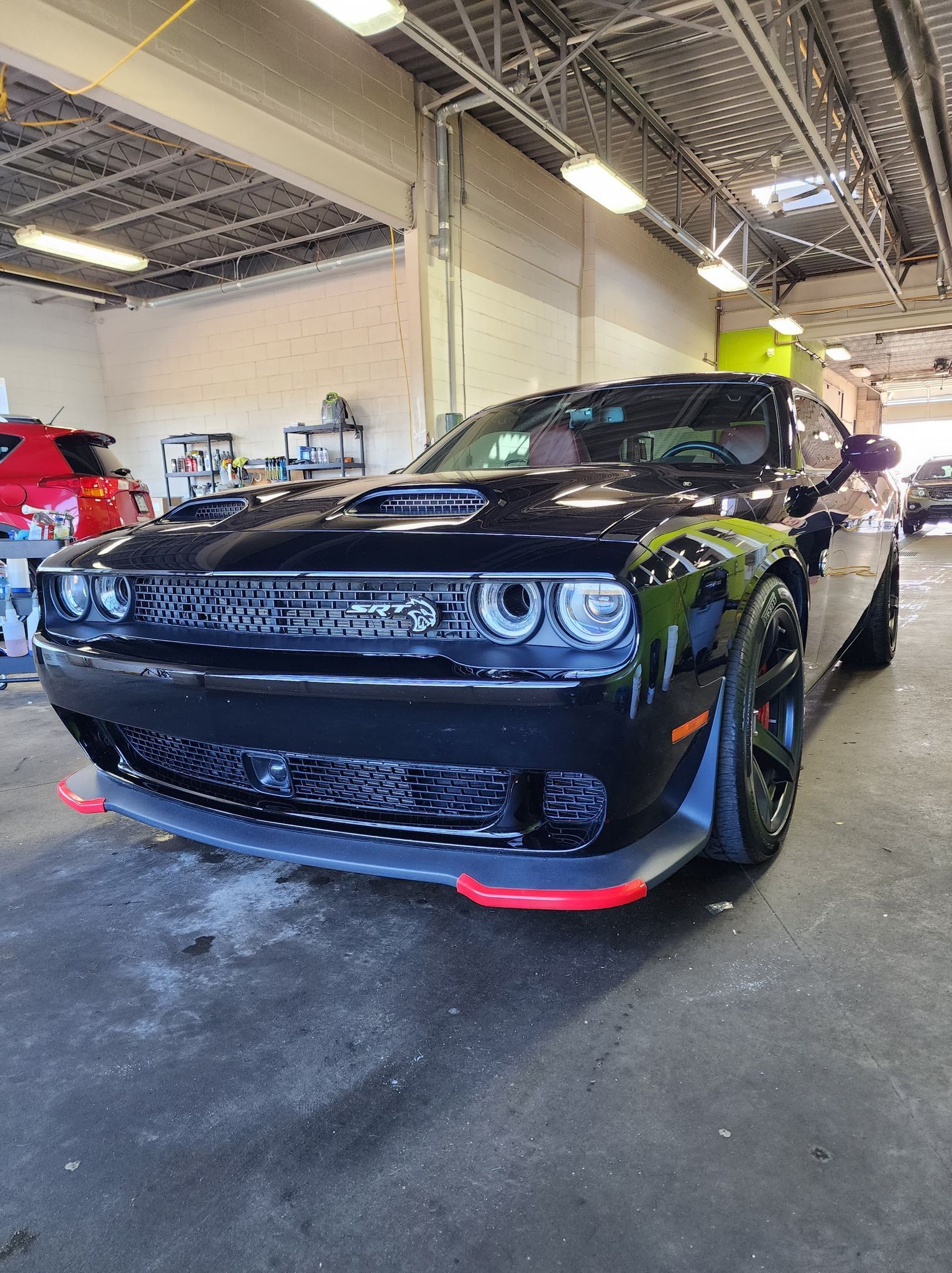 Une Dodge Challenger noire est garée dans un garage.