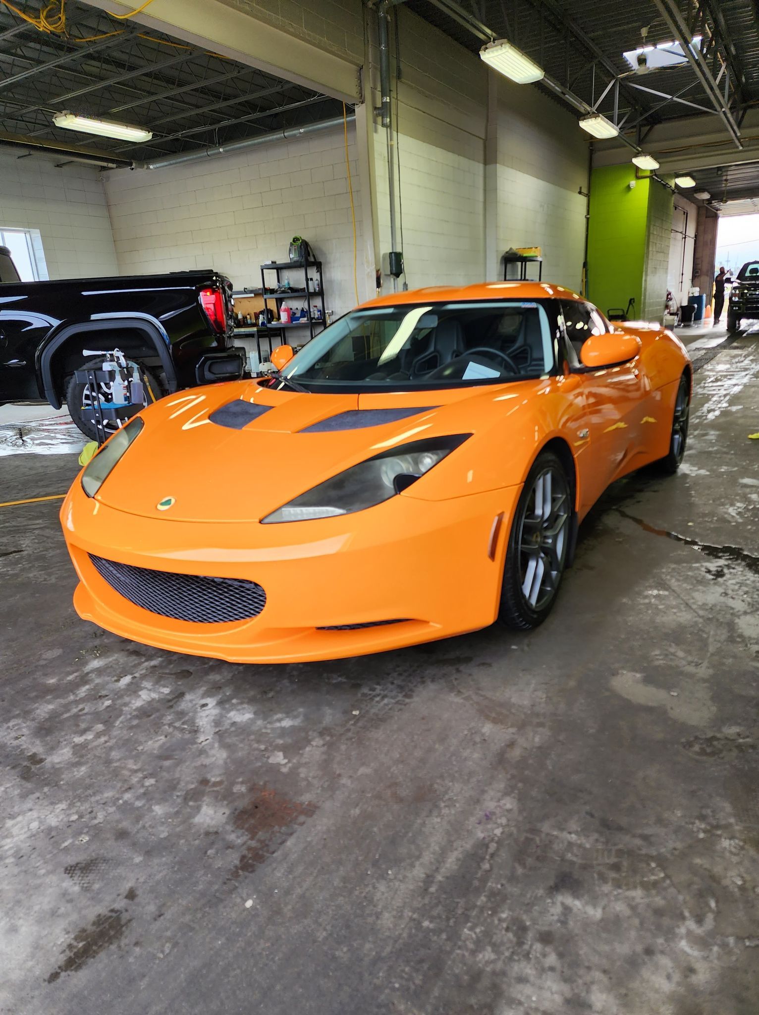 Une voiture de sport orange est garée dans un garage.