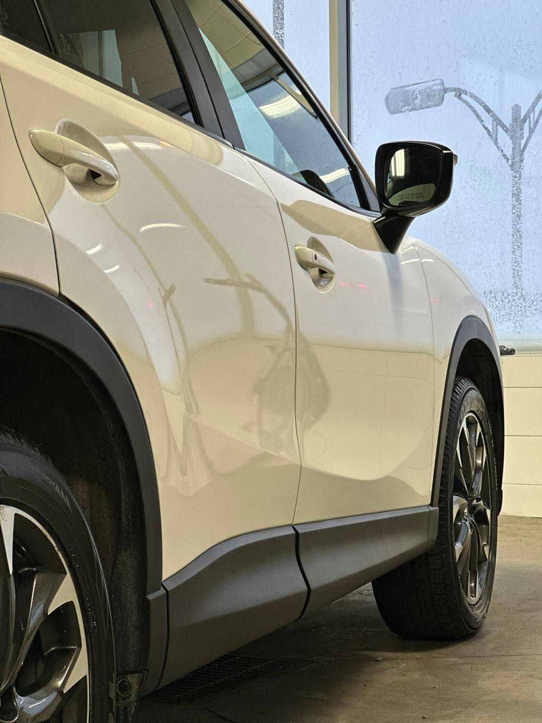 Une voiture blanche est garée devant une fenêtre