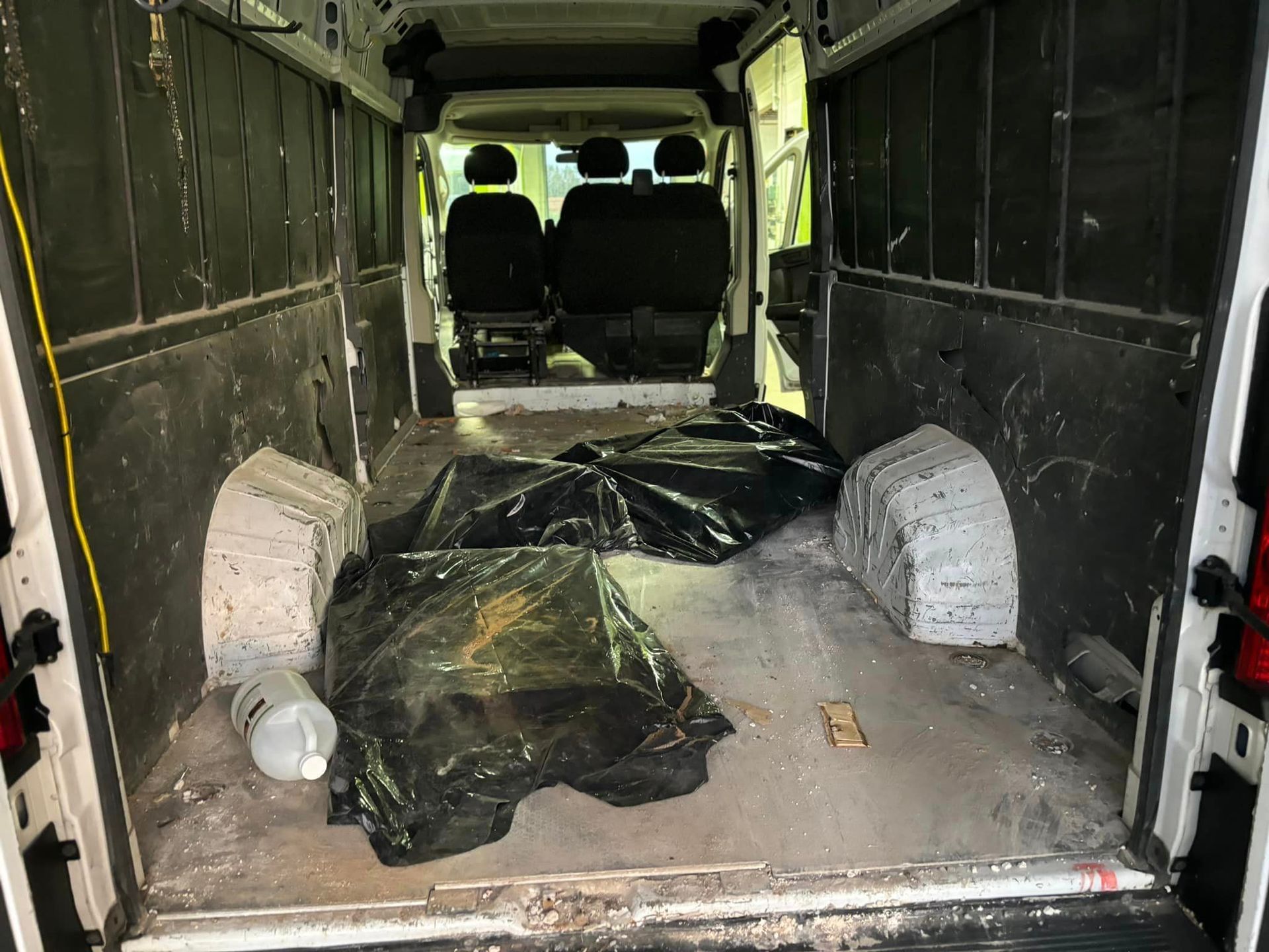 L'intérieur d'une camionnette blanche avec une bâche noire sur le sol.