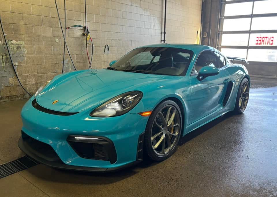 Une Porsche Boxster GT4 bleue est garée dans un garage.