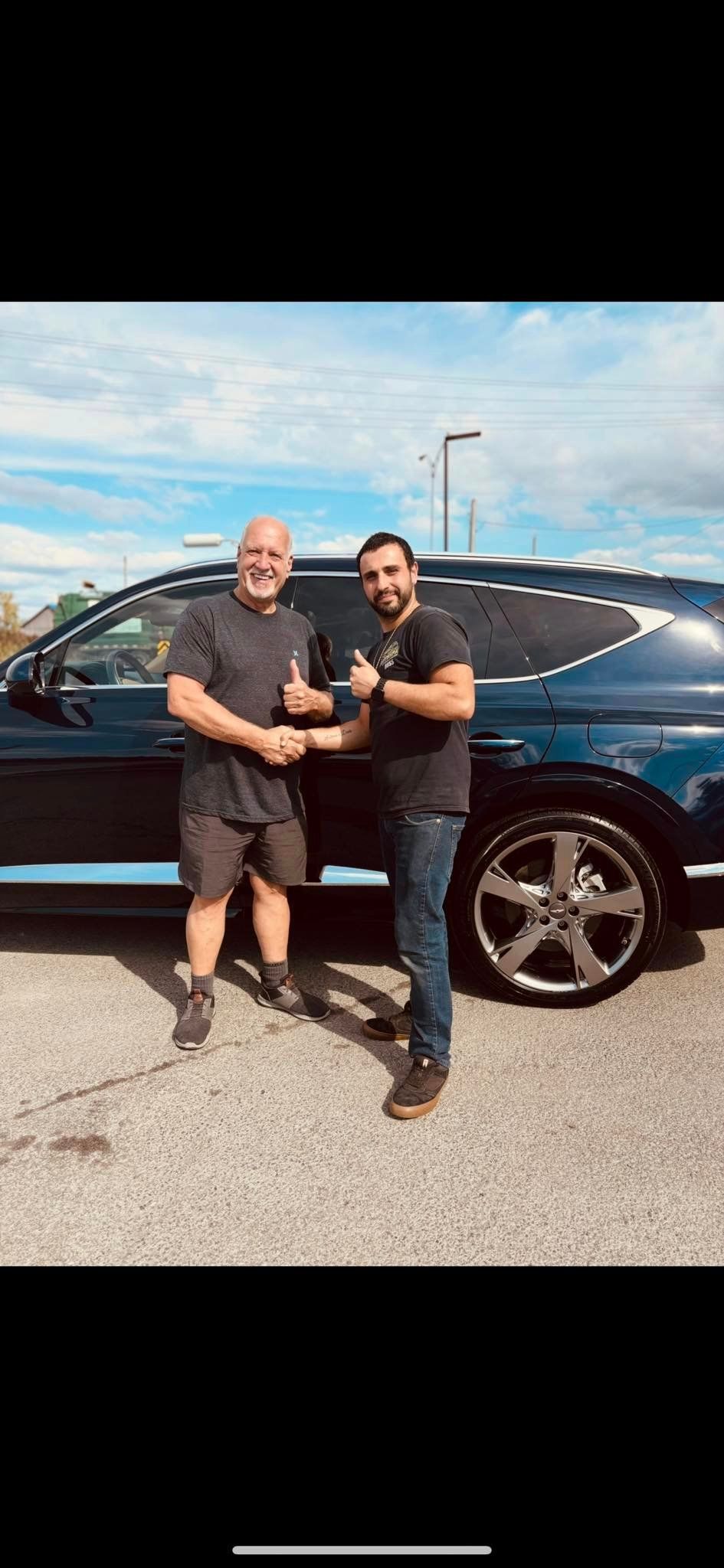 Deux hommes se serrent la main devant un SUV bleu.