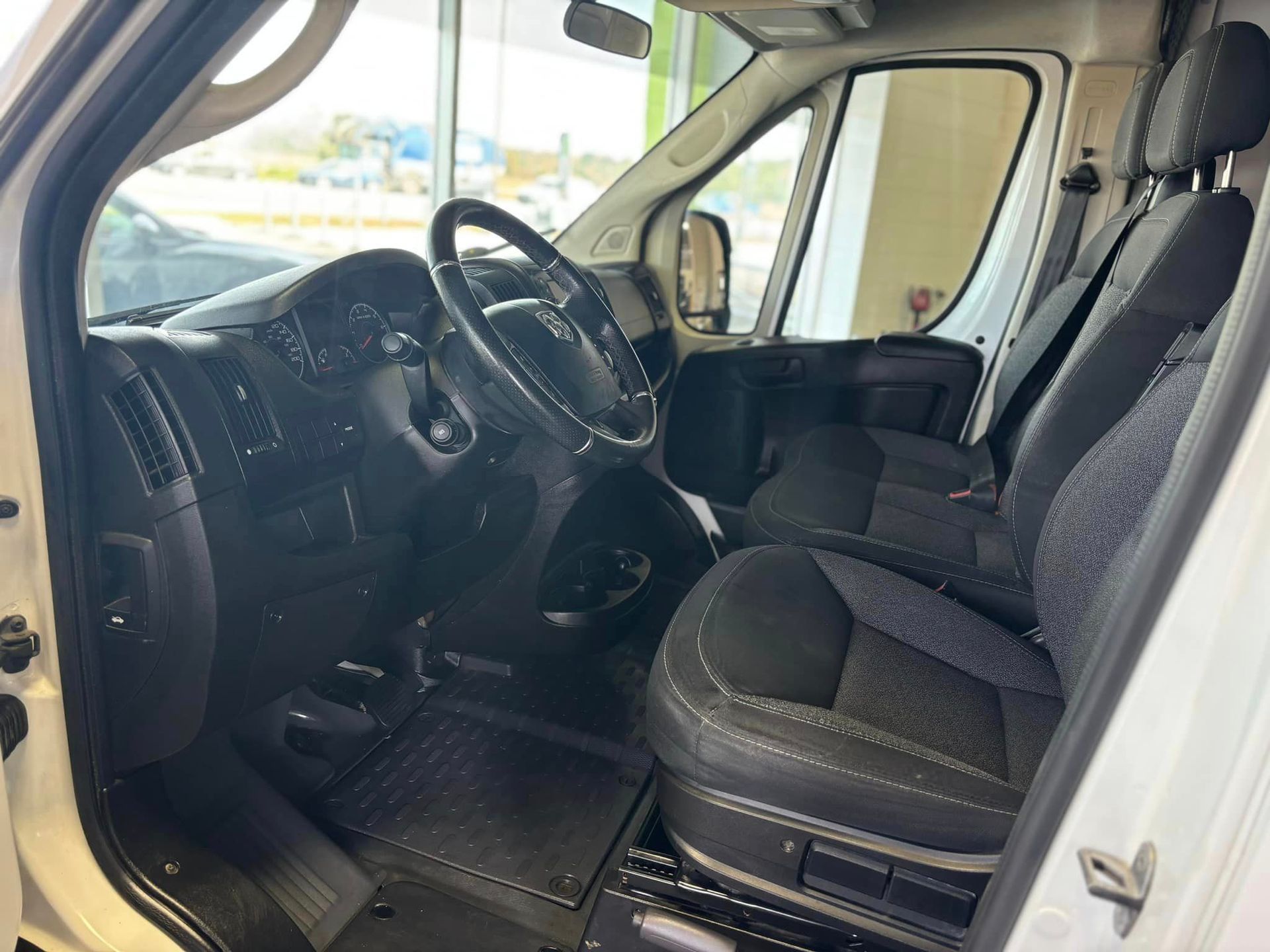 L'intérieur d'une camionnette blanche avec des sièges noirs et un volant.