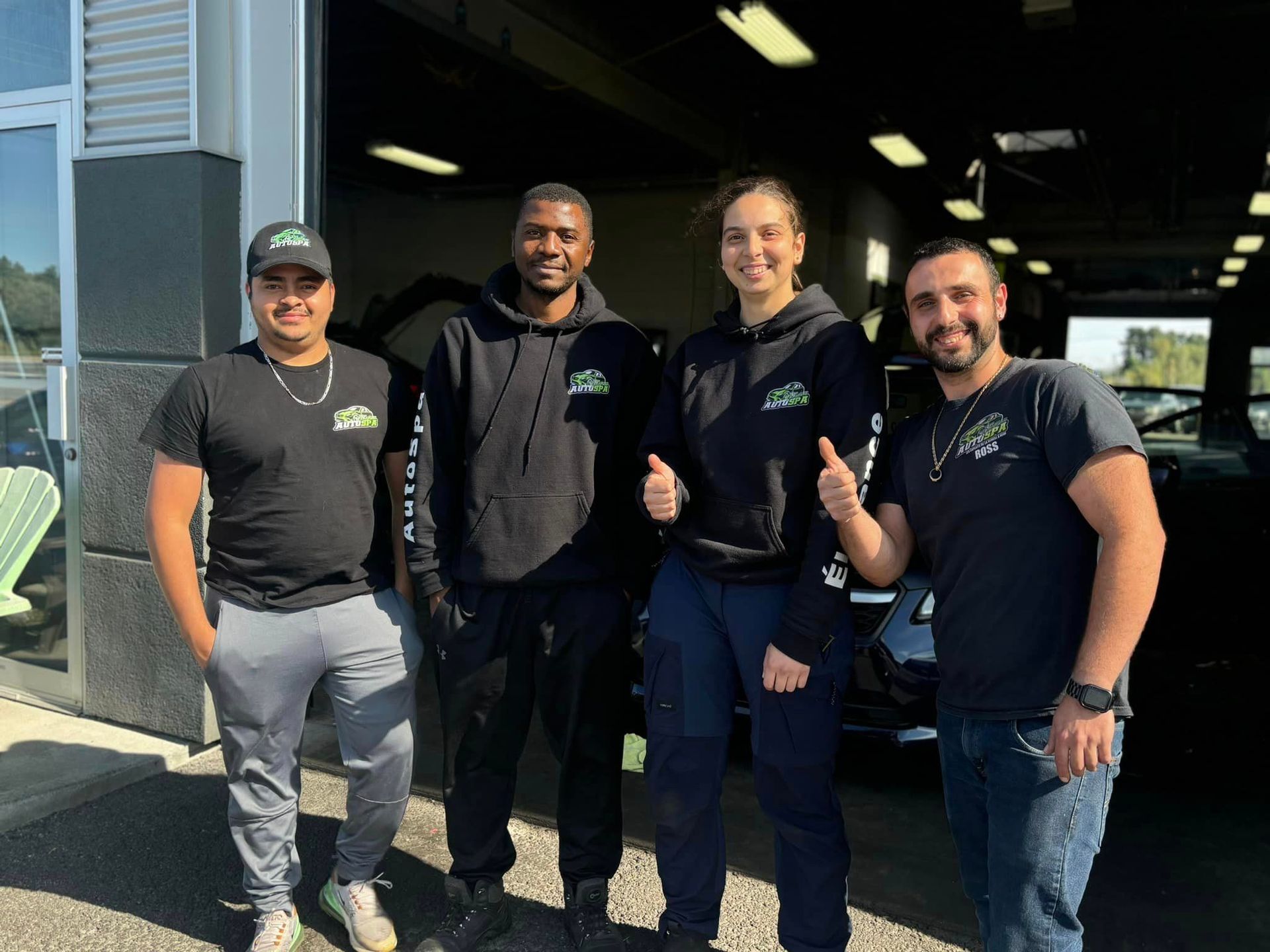 Un groupe de personnes pose pour une photo devant un concessionnaire automobile.
