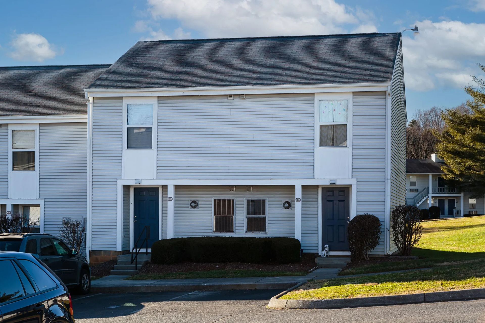Two-story gray townhouse with blue doors and windows, set in a residential neighborhood.